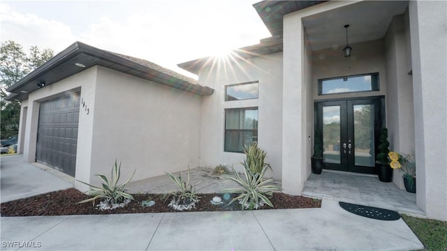 property entrance with a garage, french doors, and stucco siding