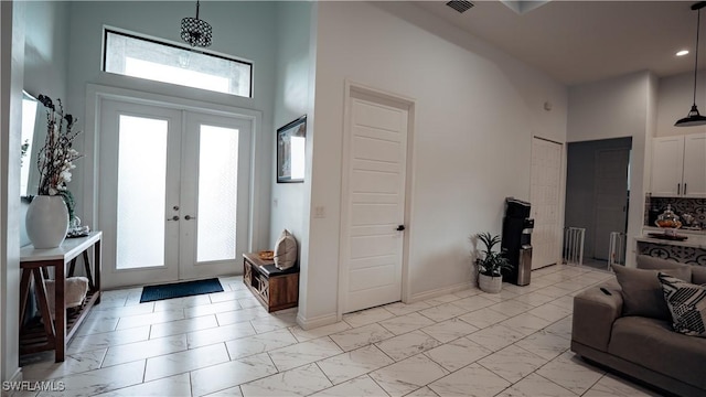 foyer with a healthy amount of sunlight, marble finish floor, a towering ceiling, and french doors