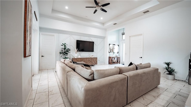 living room featuring ceiling fan, marble finish floor, a raised ceiling, and visible vents