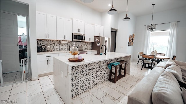 kitchen with marble finish floor, stainless steel appliances, decorative backsplash, white cabinetry, and a sink