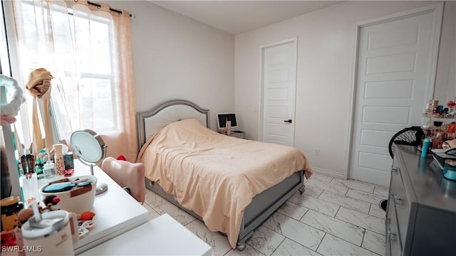 bedroom featuring marble finish floor and baseboards