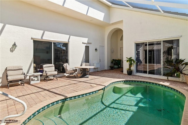 back of house featuring a lanai, a patio, and stucco siding