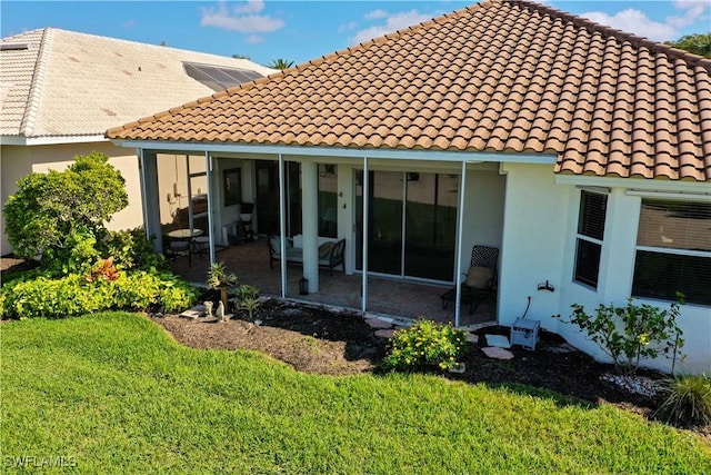 rear view of property with a sunroom, a tile roof, stucco siding, and a yard