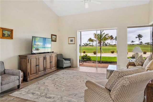 living area featuring high vaulted ceiling, light wood-style flooring, and a ceiling fan