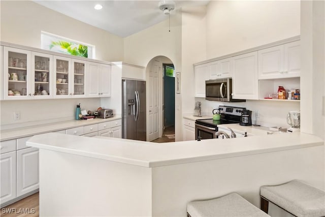 kitchen featuring a peninsula, arched walkways, stainless steel appliances, and light countertops