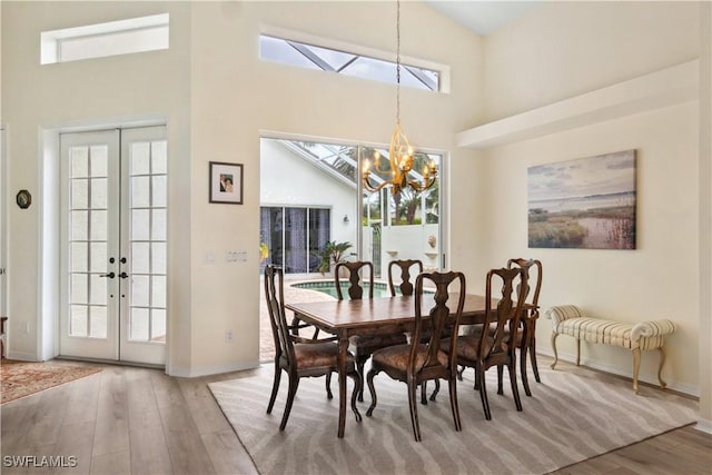 dining area with a chandelier, french doors, and wood finished floors