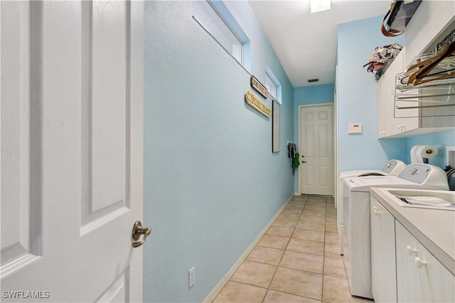 clothes washing area with light tile patterned floors, washer and clothes dryer, cabinet space, and baseboards