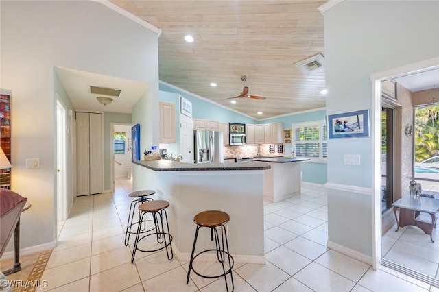 kitchen featuring appliances with stainless steel finishes, dark countertops, a kitchen breakfast bar, and light tile patterned floors