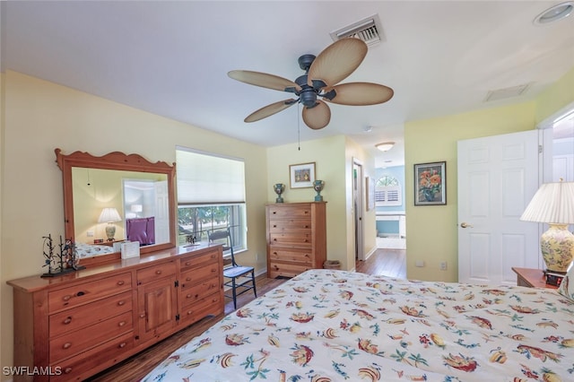 bedroom with a ceiling fan, visible vents, wood finished floors, and ensuite bathroom