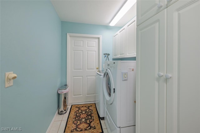 clothes washing area with light tile patterned floors, washer and clothes dryer, and cabinet space