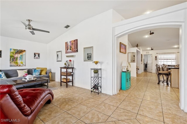 living area featuring light tile patterned floors, visible vents, arched walkways, lofted ceiling, and ceiling fan