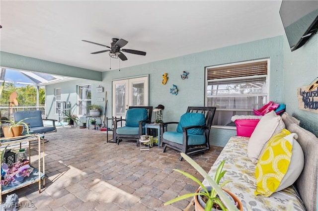 view of patio / terrace with glass enclosure, a ceiling fan, and french doors