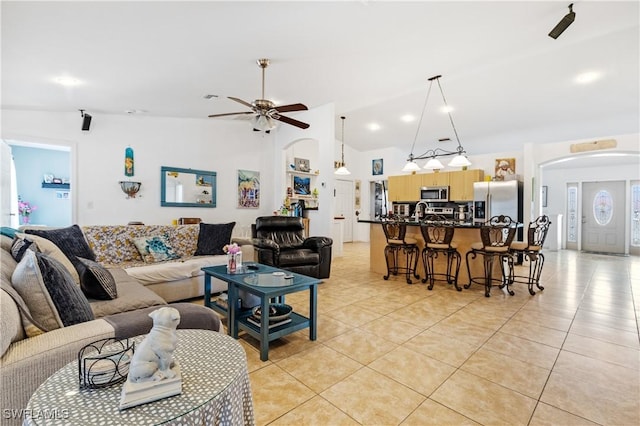 living room with arched walkways, light tile patterned floors, visible vents, a ceiling fan, and high vaulted ceiling