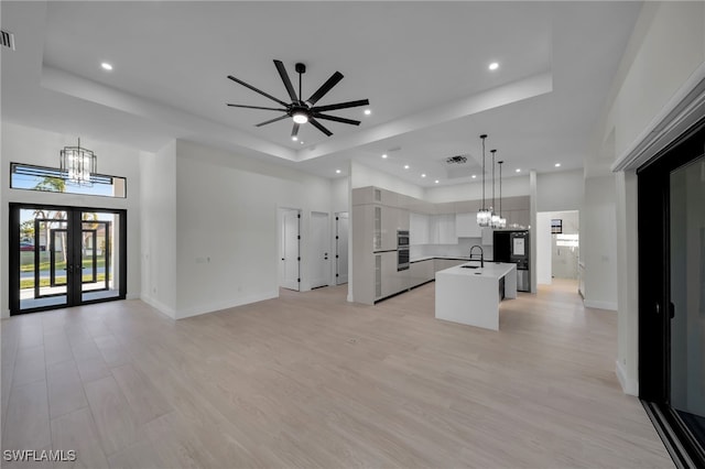 kitchen with a tray ceiling, open floor plan, and a sink