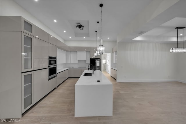 kitchen with modern cabinets, glass insert cabinets, open floor plan, stainless steel double oven, and a sink