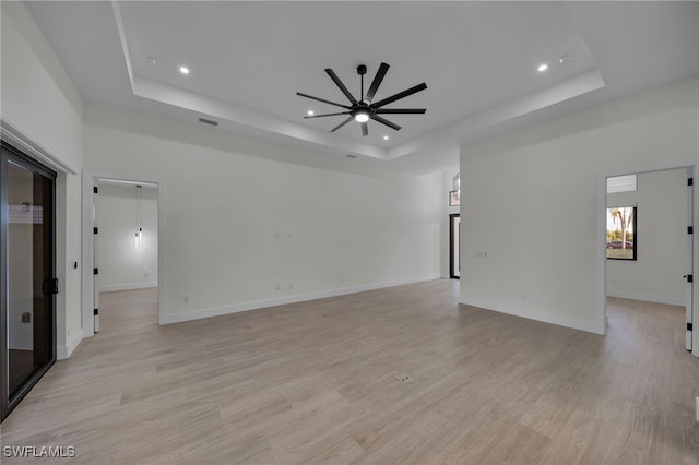 unfurnished room with light wood finished floors, baseboards, a tray ceiling, and ceiling fan