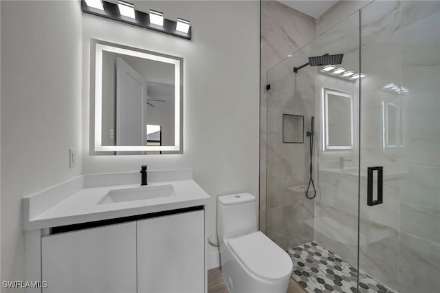 bathroom with a stall shower, vanity, and toilet