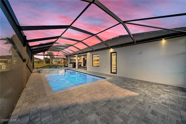 view of pool featuring a patio, glass enclosure, and a pool with connected hot tub