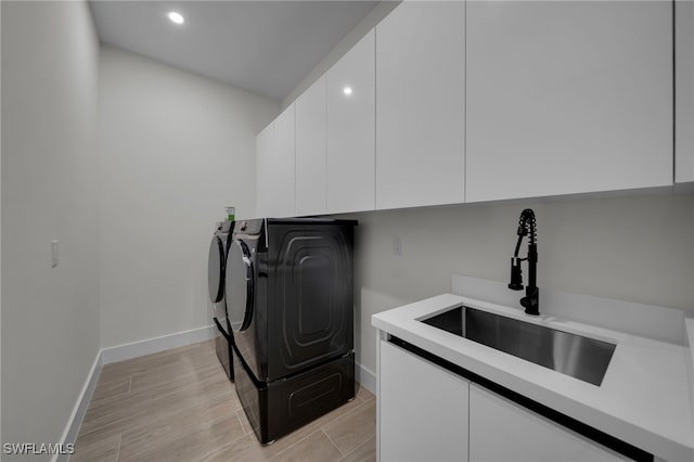 laundry area with separate washer and dryer, wood finish floors, a sink, baseboards, and cabinet space