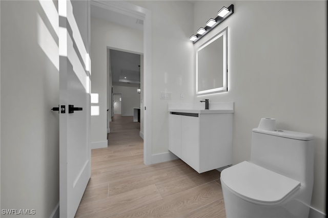 bathroom featuring baseboards, vanity, toilet, and wood finished floors