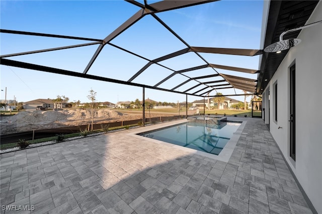 view of pool with glass enclosure, a pool with connected hot tub, and a patio area