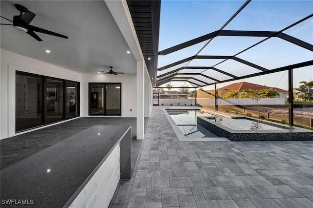 view of patio / terrace featuring ceiling fan, a lanai, an in ground hot tub, fence, and an outdoor pool