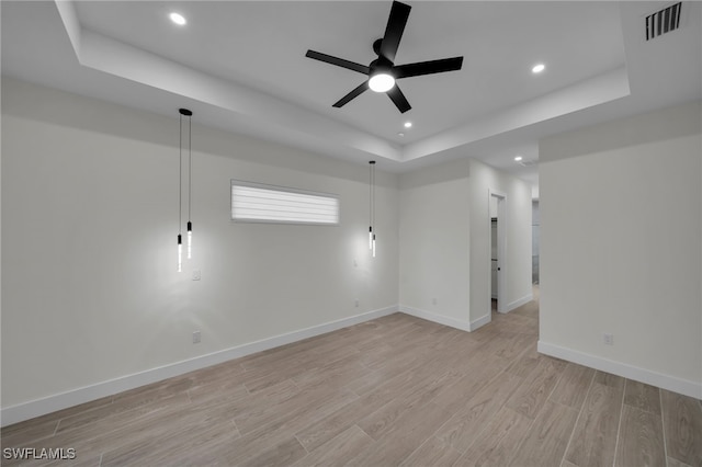 spare room with ceiling fan, recessed lighting, baseboards, light wood-style floors, and a tray ceiling