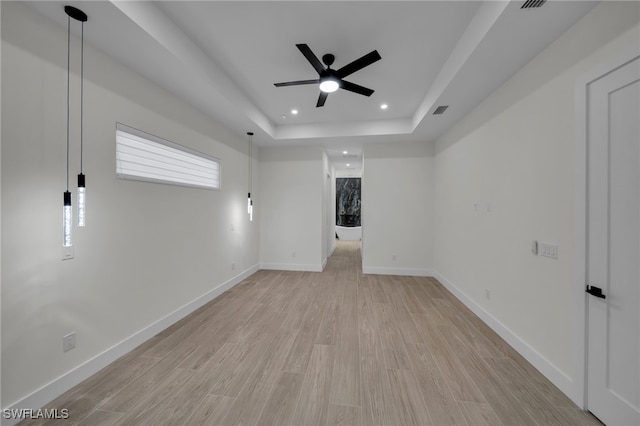 spare room with light wood finished floors, baseboards, visible vents, a tray ceiling, and recessed lighting