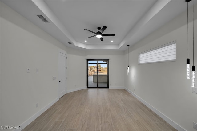 spare room featuring visible vents, baseboards, a tray ceiling, light wood-style floors, and recessed lighting