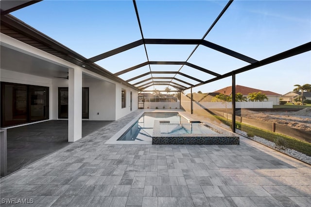 pool featuring glass enclosure, a patio area, and an in ground hot tub