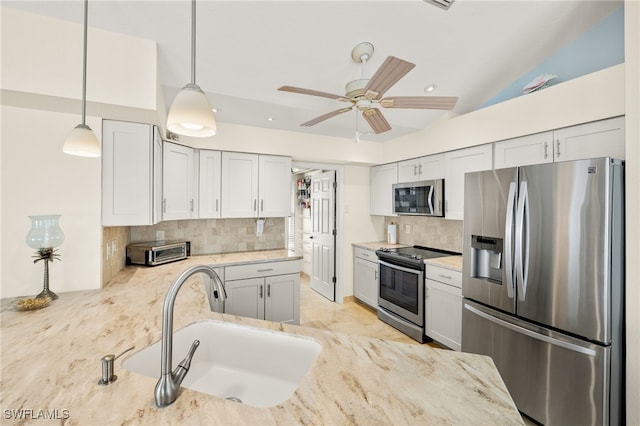 kitchen with a sink, stainless steel appliances, white cabinets, decorative backsplash, and hanging light fixtures