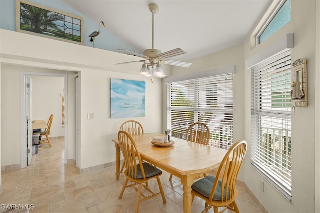 dining room featuring stone tile floors, a healthy amount of sunlight, baseboards, and ceiling fan