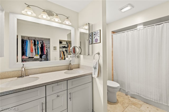 bathroom featuring a sink, toilet, a shower with shower curtain, and double vanity