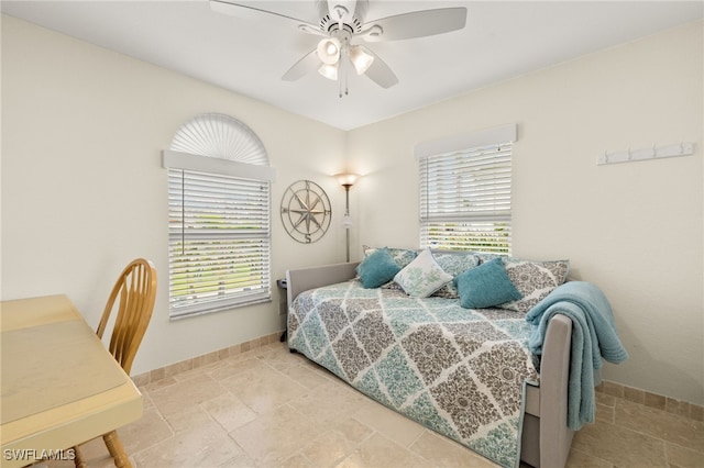 bedroom featuring baseboards, a ceiling fan, and stone finish floor