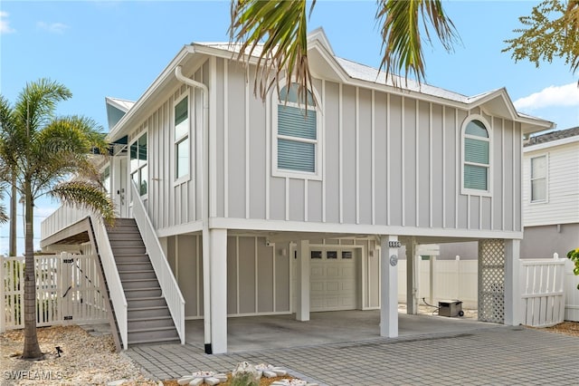 exterior space with fence, an attached garage, stairs, decorative driveway, and board and batten siding