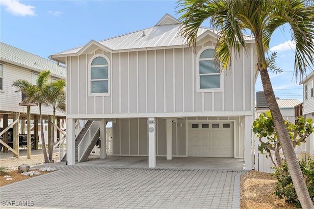 view of front of property with board and batten siding, stairway, metal roof, decorative driveway, and a carport