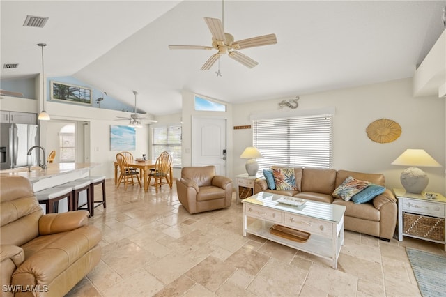 living area featuring stone tile flooring, visible vents, and a ceiling fan