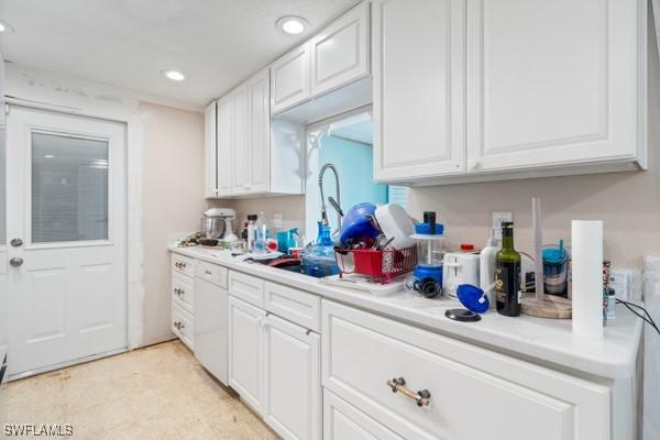 kitchen with a sink, white cabinets, dishwasher, and light countertops