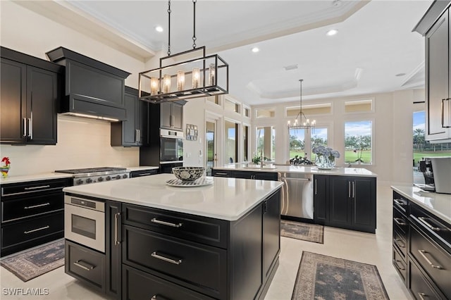 kitchen featuring a center island, a tray ceiling, light countertops, appliances with stainless steel finishes, and dark cabinets