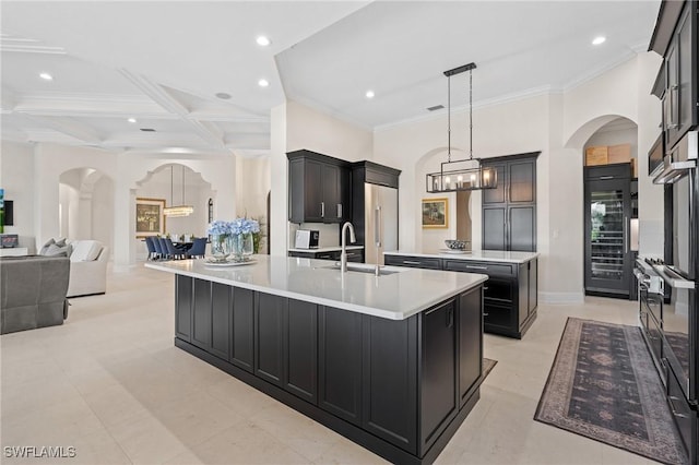 kitchen with arched walkways, built in fridge, a large island, and a sink