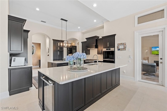 kitchen with beverage cooler, arched walkways, a spacious island, oven, and a sink