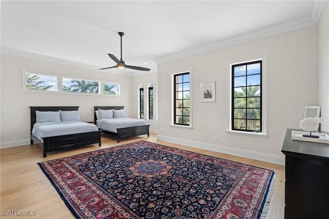 bedroom with ornamental molding, light wood-type flooring, a ceiling fan, and baseboards