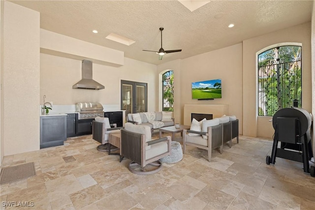 living room featuring recessed lighting, stone finish floor, ceiling fan, and a textured ceiling