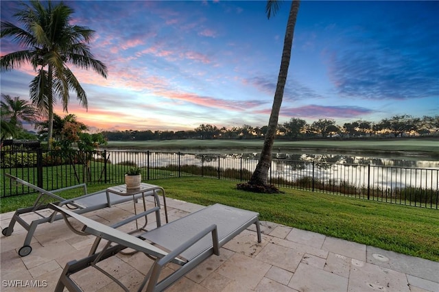 view of community with a yard, a water view, a patio, and a fenced backyard