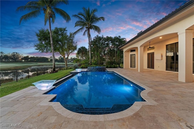 view of swimming pool featuring a patio area, fence, a pool with connected hot tub, and a water view