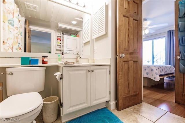 ensuite bathroom with visible vents, connected bathroom, toilet, vanity, and stacked washing maching and dryer