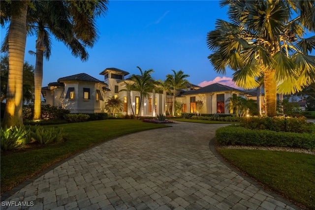 mediterranean / spanish house featuring a front lawn, decorative driveway, and stucco siding