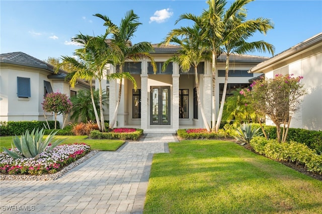 view of exterior entry featuring a lawn and stucco siding