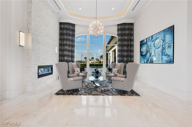 sitting room with baseboards, a towering ceiling, a tray ceiling, a fireplace, and a notable chandelier