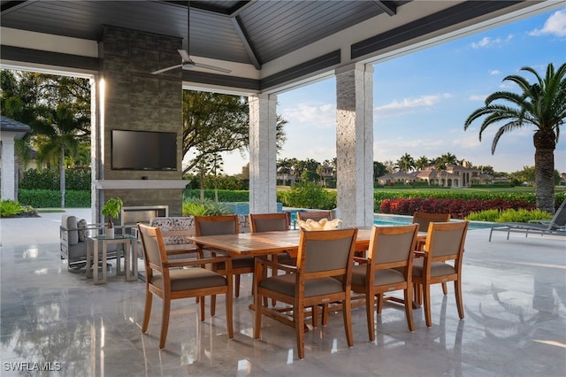 view of patio / terrace with a fireplace, a ceiling fan, and outdoor dining space